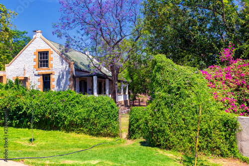 Traditional south african countryside house and garden with blooming trees and bushes