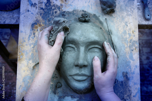 Fototapeta The hands of the sculptor mold the clay mask