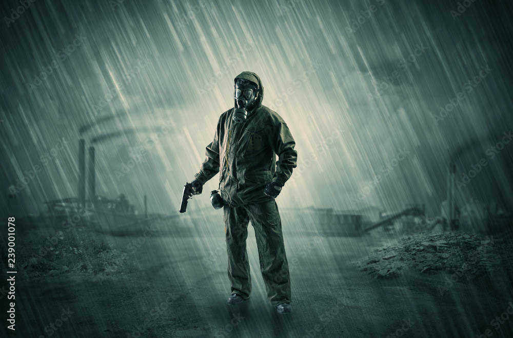 Fototapeta premium Gas masked survival man coming with arms on his hand in a demolished dark environment 