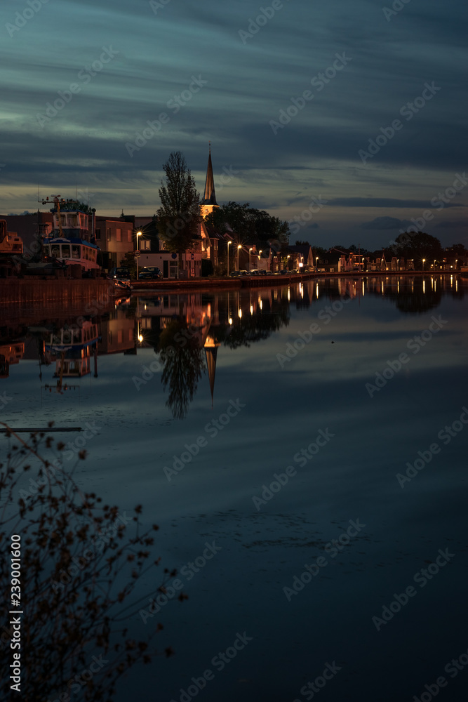 View of a town with church near Gouda, Holland at blue hour. Beautiful reflections of a moody sky.