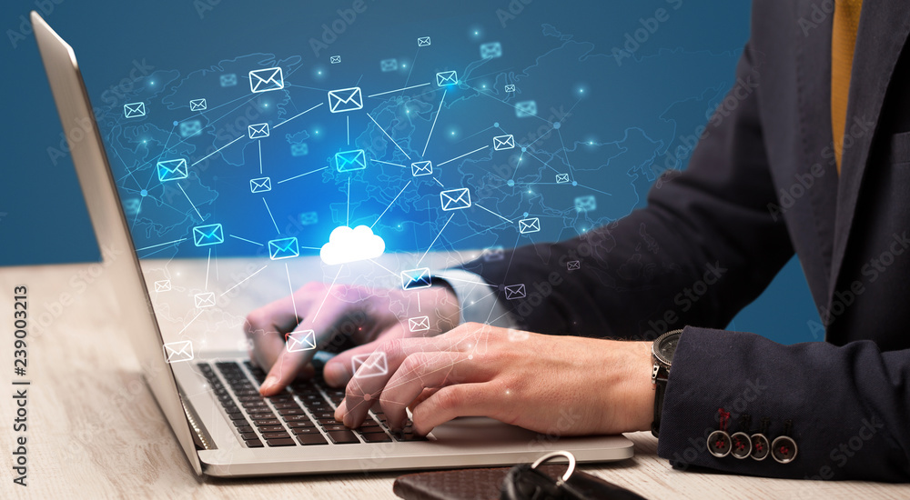 Fototapeta premium Businessman hand sending a bunch of messages on laptop with cloud computing concept