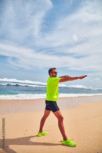 Sportsman stretching on a exotic tropical beach after jogging / exercising.