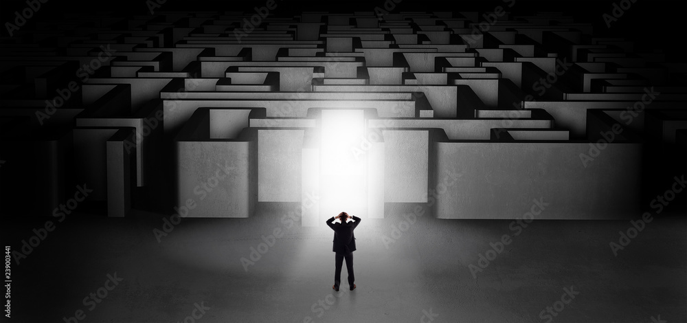 Lost businessman standing at the dark labyrinth with illuminated door
Lost businessman standing at the dark labyrinth with illuminated door