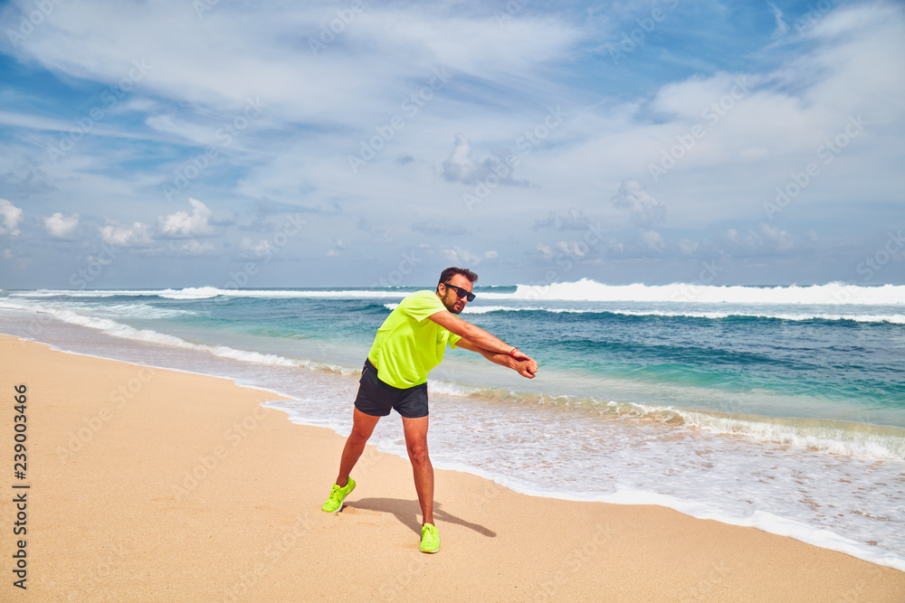 Sportsman stretching on a exotic tropical beach after jogging / exercising. Sportsman stretching on a exotic tropical beach after jogging / exercising.