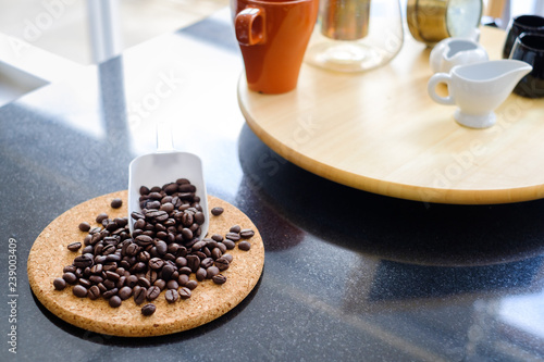 Coffee beans on trencher and white scoop with  black stone top table and fullset off coffee background. photo