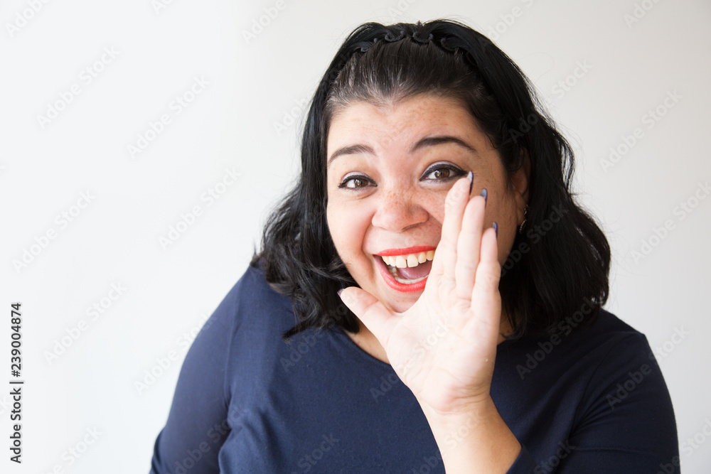 Excited Hispanic woman yelling about discount with hand near mouth. Cheerful Latin overweight woman shouting about advertisement. Isolated on white. Advertising concept Excited Hispanic woman yelling about discount with hand near mouth. Cheerful Latin overweight woman shouting about advertisement. Isolated on white. Advertising concept