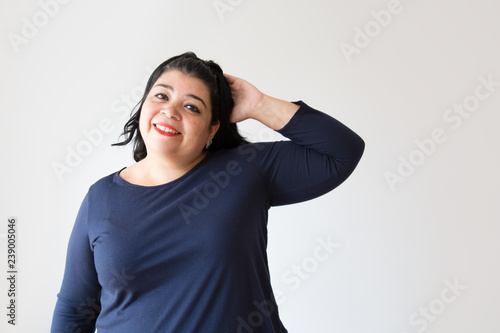 Overweight pensive Hispanic woman scratching head. Thoughtful plus size woman looking at camera. Isolated on white. Thinking concept © KAMPUS