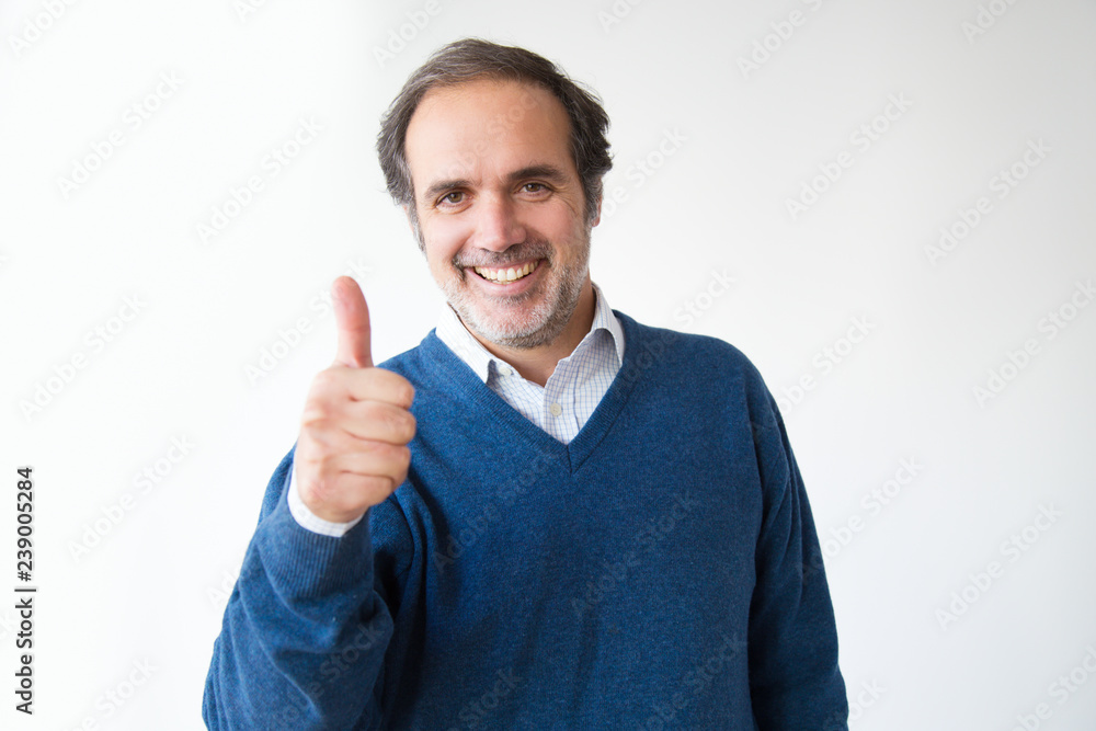 Smiling Caucasian man showing thumb up. Positive mature man gesturing thumb up and looking at camera. Isolated on white. Joyfulness concept Smiling Caucasian man showing thumb up. Positive mature man gesturing thumb up and looking at camera. Isolated on white. Joyfulness concept