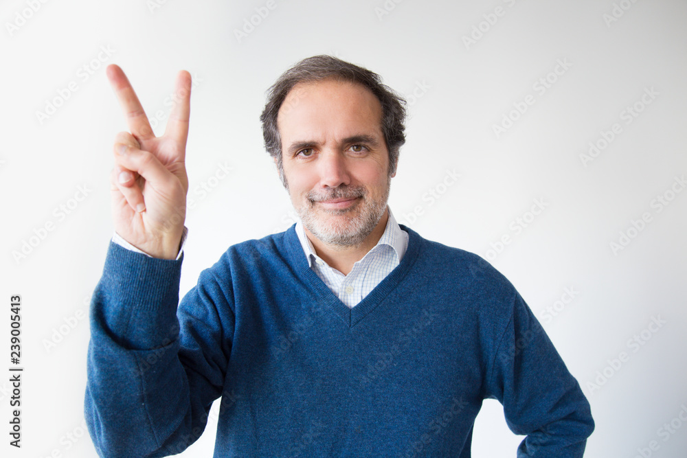 Smiling mature man showing peace symbol. Cheerful middle aged man showing victory sign and looking at camera. Isolated on white. Motivation concept Smiling mature man showing peace symbol. Cheerful middle aged man showing victory sign and looking at camera. Isolated on white. Motivation concept
