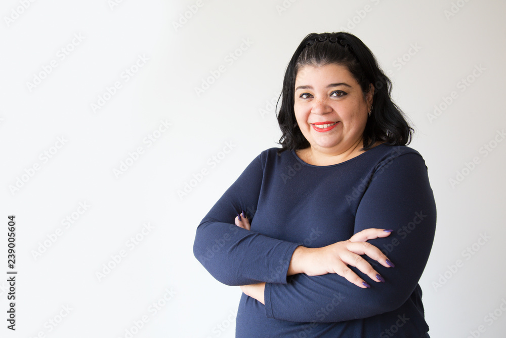 Successful overweight Hispanic woman posing with crossed arms. Smiling adult plus size woman looking at camera. Isolated on white. Success concept Successful overweight Hispanic woman posing with crossed arms. Smiling adult plus size woman looking at camera. Isolated on white. Success concept