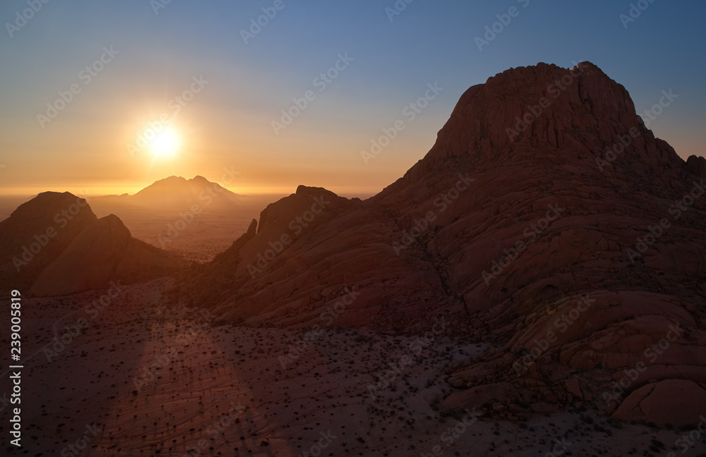 Panoramic, aerial view on a silhouette of a ancient Spitzkoppe mountain against sunset. Rocky desert landscape. Travelling to remote place in Namibia.