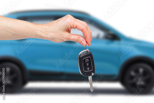 Female hand holds the keys to the new car on the background of the blue car