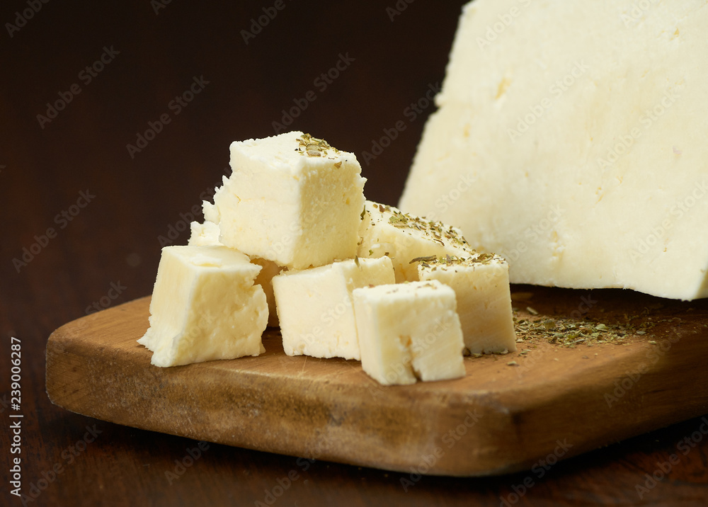 Pieces of delicate white cheese on a wooden plank.