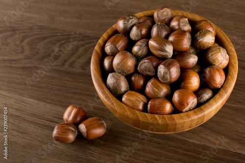 Hazelnuts in wooded bowl isolated on wood background, top view, copy space