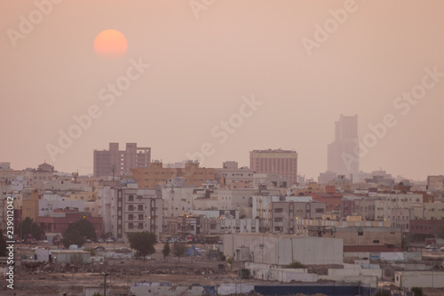 Sunset over modern office buildings in business district center of Jeddah Saudi Arabia. Skyline view of cityscape with sunlight and flare in warm light color tone. Construction business concept. 