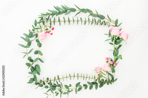 Floral wreath frame of pink roses and eucalyptus branches on white background. Flat lay, top view