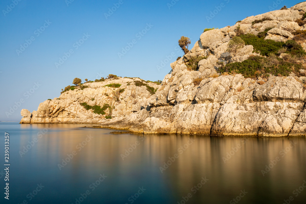 Felsklippen mit Spiegelung in der glatten Wasseroberfläche des Mittelmeeres bei einer Aufnahme mit Langzeitbelichtung