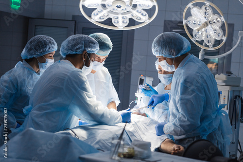 Group of concentrated surgeons engaging in rescue of male patient in operation room at hospital, emergency case, surgery, medical technology, health care and disease treatment concept
