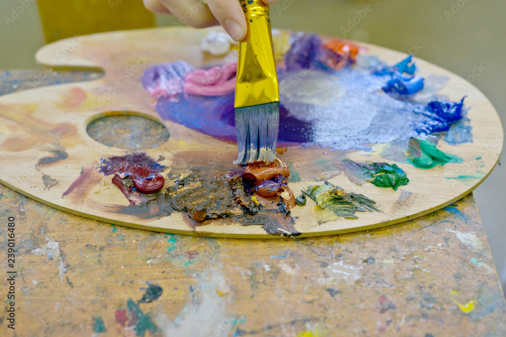 Close up of woman's hand mix paints with brush in palette in art-class Close up of woman's hand mix paints with brush in palette in art-class
