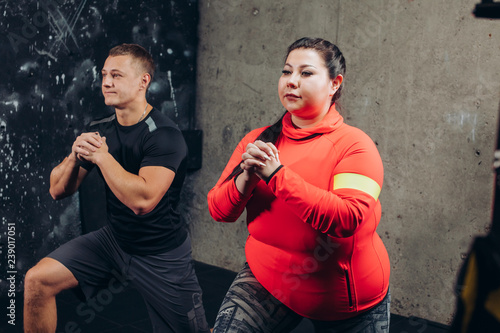 plump woman with a sporty man doing exercises in the sport center. close up side view photo. interest, lifestyle © alfa27