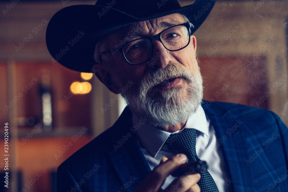 Εκτύπωση καμβά Thoughtful, selective, male aged investor in glasses, smoking cigar, fume, hold