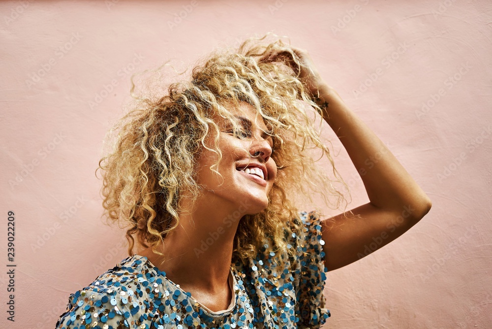 Φωτογραφία portrait of an attractive blonde female smiling and touching her hair curly hair