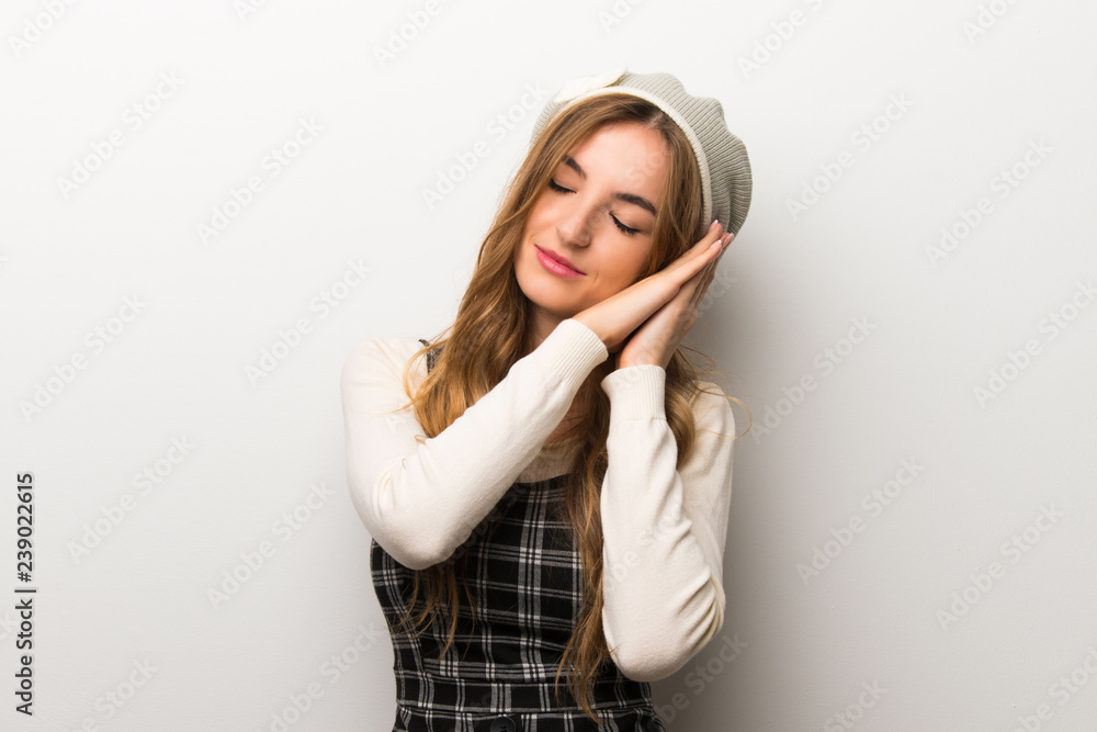 Fashionably woman wearing hat making sleep gesture in dorable expression