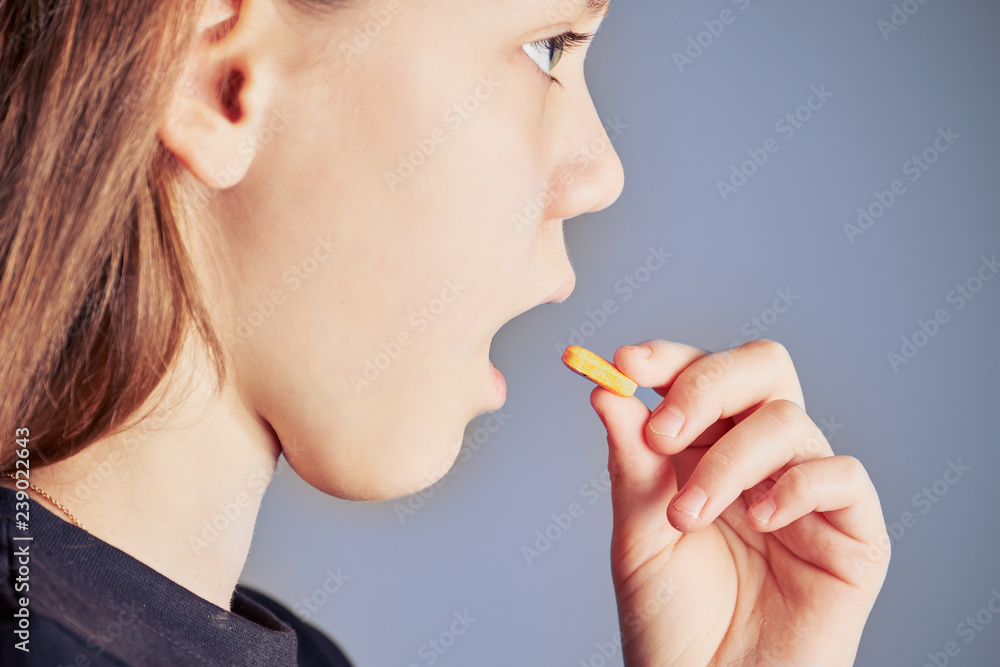 Unhealthy girl puts small yellow pill in her mouth from disease. Unhealthy girl puts small yellow pill in her mouth from disease.