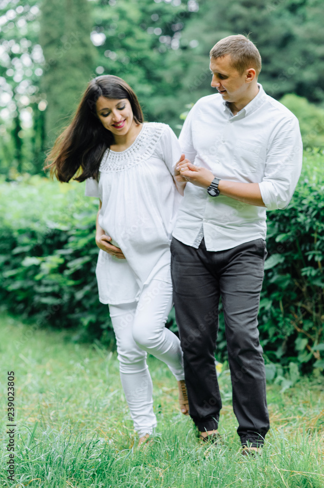 Happy and young pregnant couple hugging in nature Happy and young pregnant couple hugging in nature