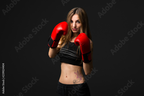 Sport woman with boxing gloves on dark background