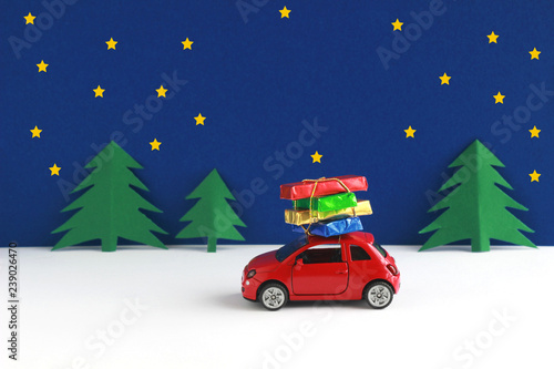 christmas card with copy space, car with parcels driving through winter landscape at night