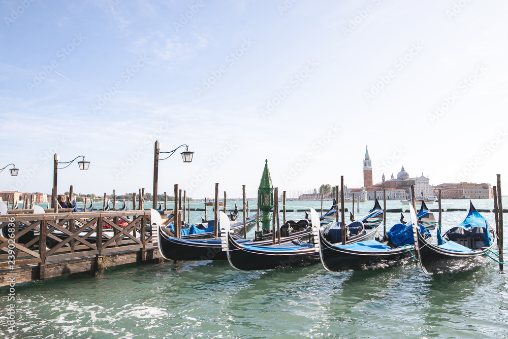 Gondolas near the seafront on the background of the sea on a bright day of summer, Venice, Italy.