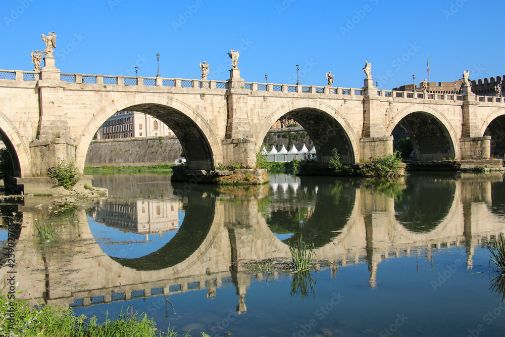 Saint Angel bridge and its reflection in the water Tiber river in Rome,Italy.