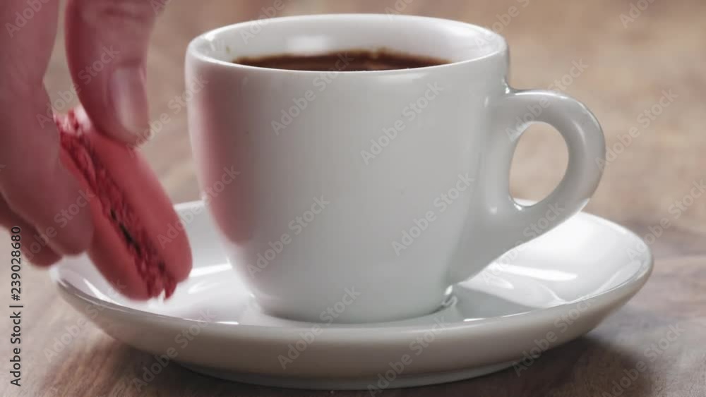 Man hand bring cup of fresh espresso with macaroon on table Man hand bring cup of fresh espresso with macaroon on table