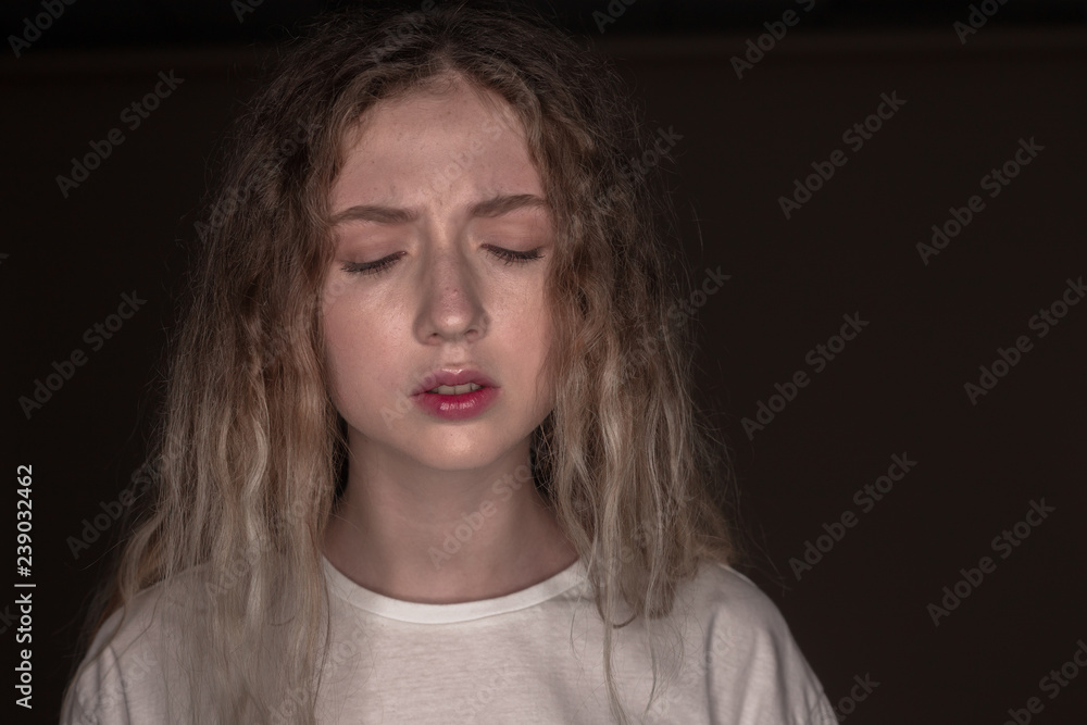 The portrait of a young girl with blonde hair isolated on a brown background The portrait of a young girl with blonde hair isolated on a brown background