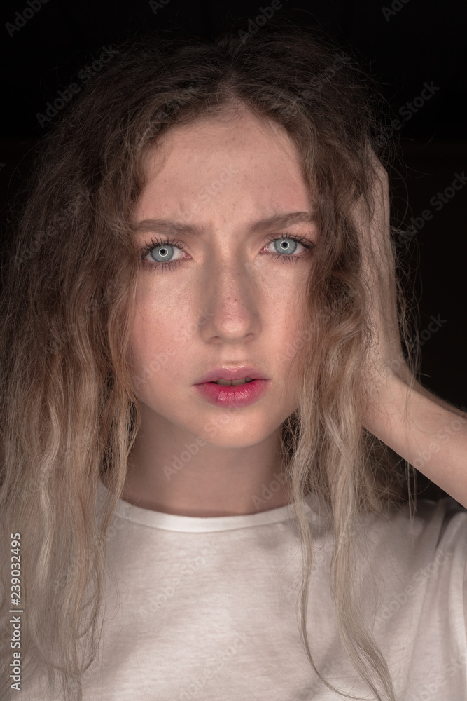 The portrait of a young girl with blonde hair isolated on a brown background The portrait of a young girl with blonde hair isolated on a brown background