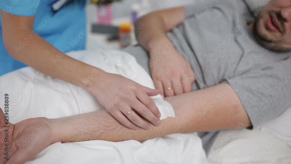 the doctor is watching the catheter on the patient's arm the doctor is watching the catheter on the patient's arm