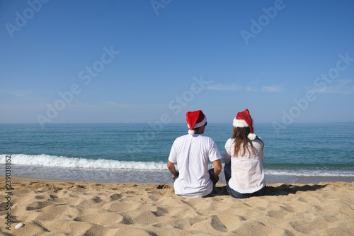 Happy Family with Santa hat at beach. Young couple in love celebrate Christmas on beach with a son