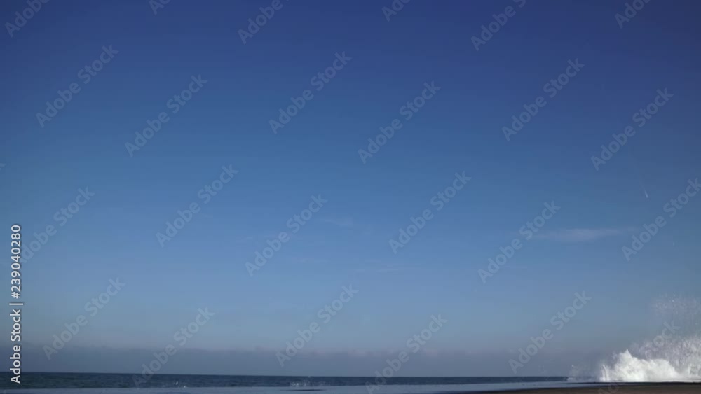 Slow motion splashes big strong waves crashing on the pier against the bright blue sky in a winter sunny day. Motion wave with splashes Slow motion splashes big strong waves crashing on the pier against the bright blue sky in a winter sunny day. Motion wave with splashes