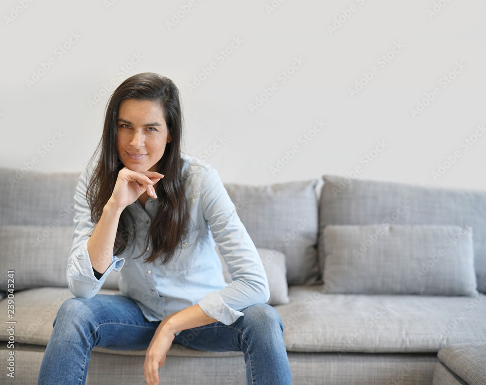 Isolated stunning brunette in denim on comfortable couch Isolated stunning brunette in denim on comfortable couch