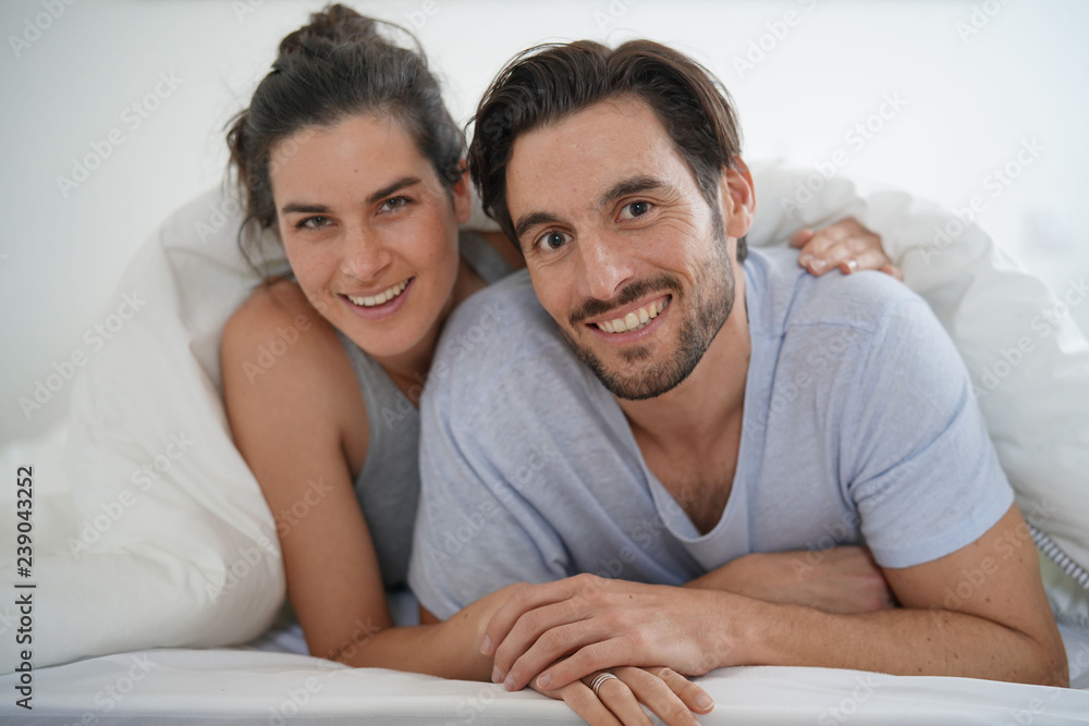 Isolated stunning couple looking at camera smiling in bed Isolated stunning couple looking at camera smiling in bed