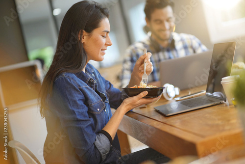Принти на полотні Beautiful woman eating lunch whilst working in co working space