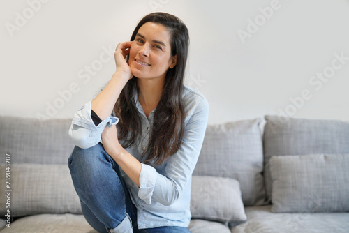 Isolated stunning brunette in denim on comfortable couch