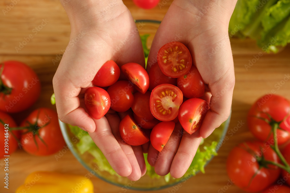 .The girl is holding fresh red cherry tomatoes. Cooking salad. .The girl is holding fresh red cherry tomatoes. Cooking salad.