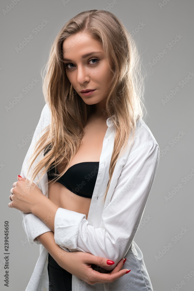 Foto de Blonde in black bra and white unbuttoned shirt do Stock
