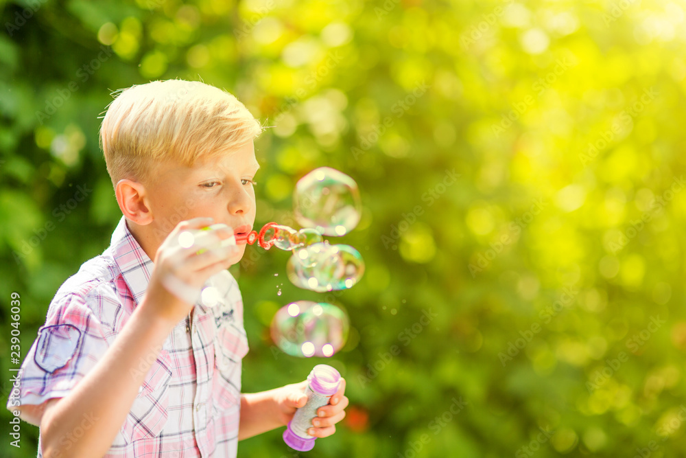 Portrait of a young boy blowing soap bubbles in a park Portrait of a young boy blowing soap bubbles in a park