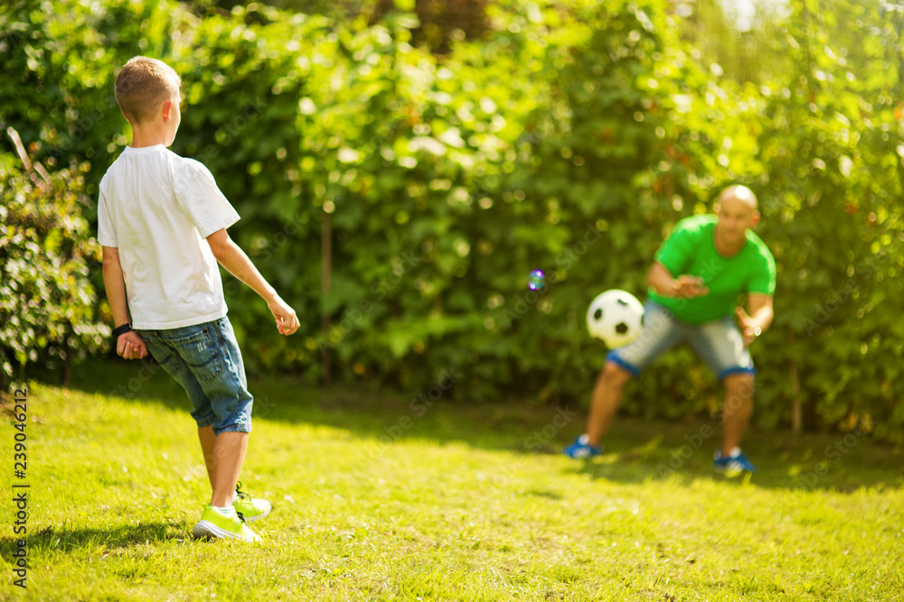 Obraz premium Son playing with his father footbal in a park, having fun