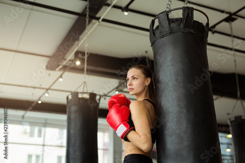 beautiful young girl in boxing gloves near the punching bag in the gym in training