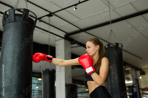 beautiful young girl is engaged in boxing with a punching bag in the gym