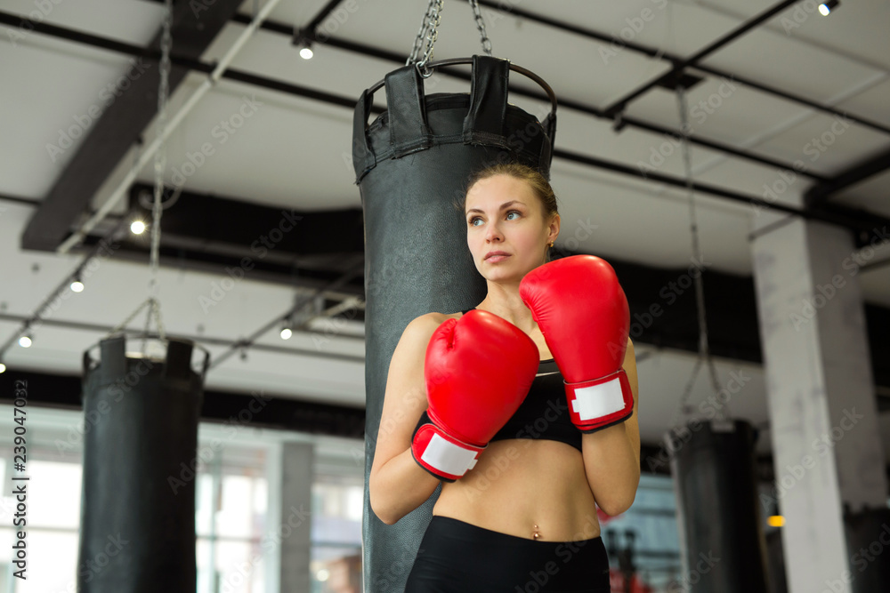 beautiful young girl in boxing gloves near the punching bag in the gym in training